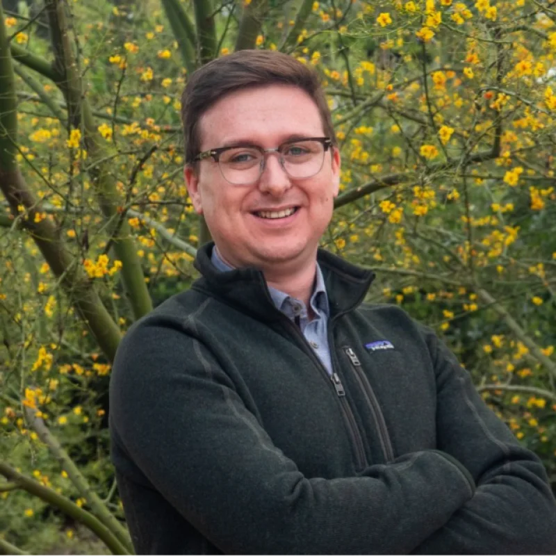 Henry Kobin outdoors in front of yellow flowering trees