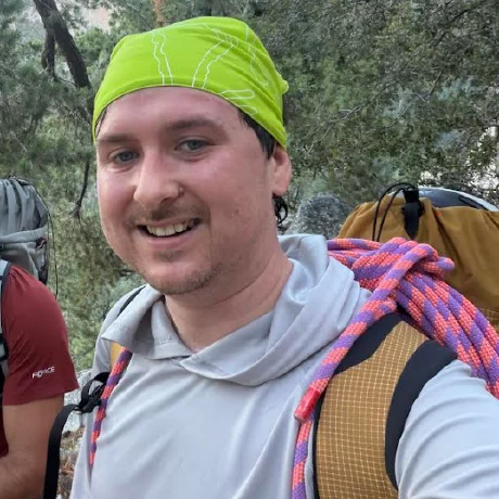 Henry Kobin outdoors with a backpack and climbing rope